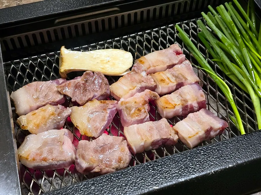 Thick-cut black pork grilling over charcoal