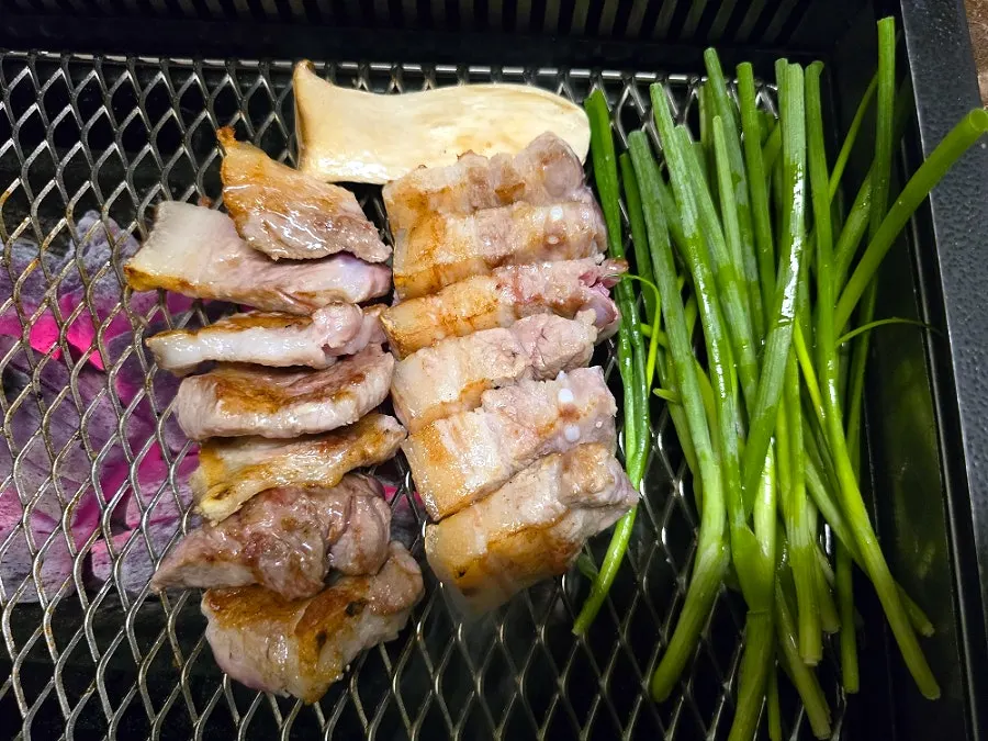 Black pork and scallions cooking on the grill