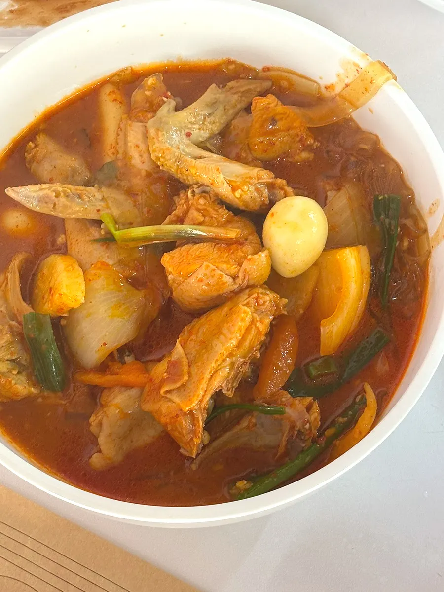 Dakdoritang served in a bowl with cheese rice cakes and quail eggs