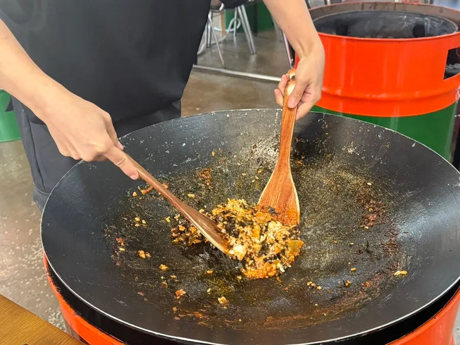 Fried rice being stir-fried in the iron lid