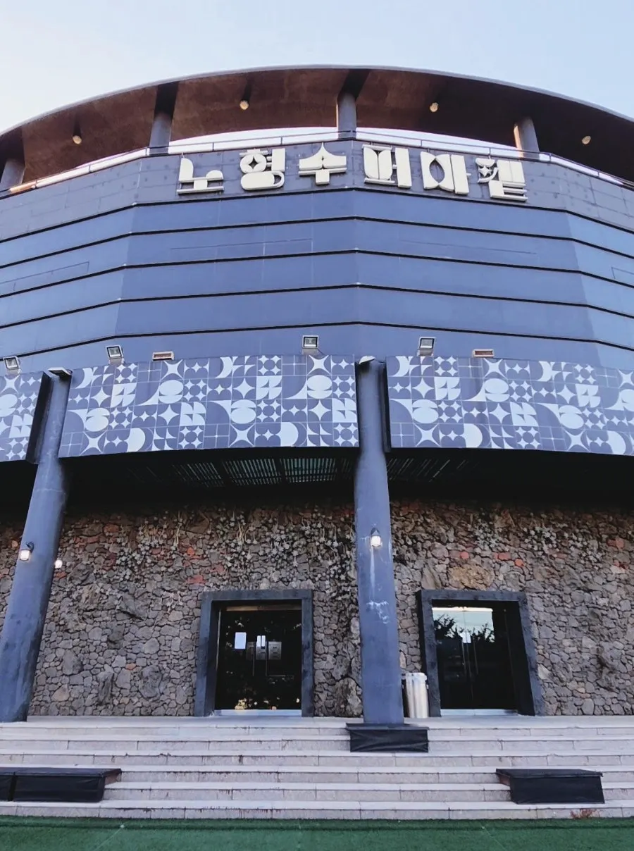 Wall reminiscent of Jeju stone walls with the large Nohyeong Supermarket sign