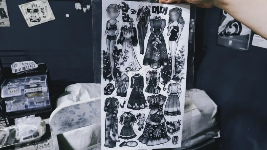 Black-and-white retro props including paper dolls and ddakji