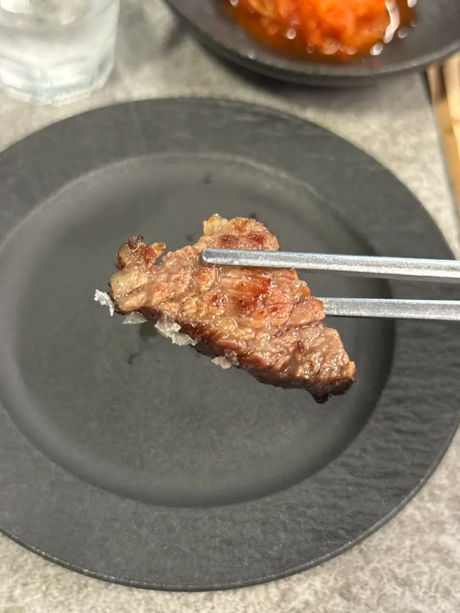 A piece of udae galbi picked up with chopsticks