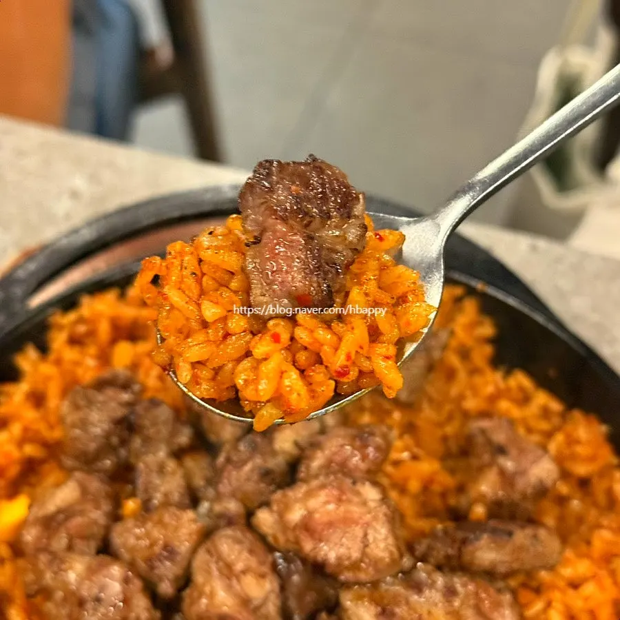 A spoonful of kkakdugi fried rice topped with meat