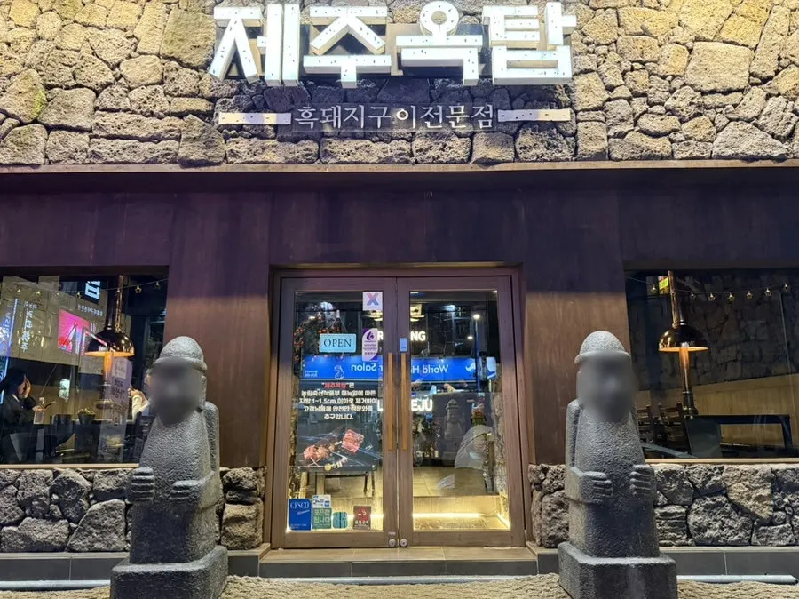 Exterior of Jeju Oktop, Gwangju Gyeongan branch, with stone walls and dol hareubang statues