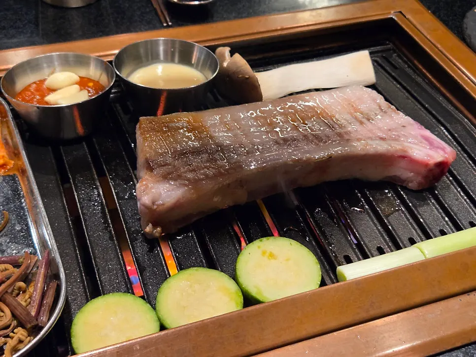직원이 그릴에서 흑돼지 삼겹살을 굽는 모습