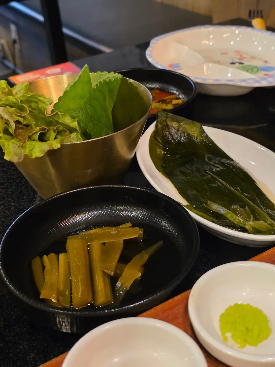 Wrapping greens, wild garlic leaves, pickled radish and other side dishes