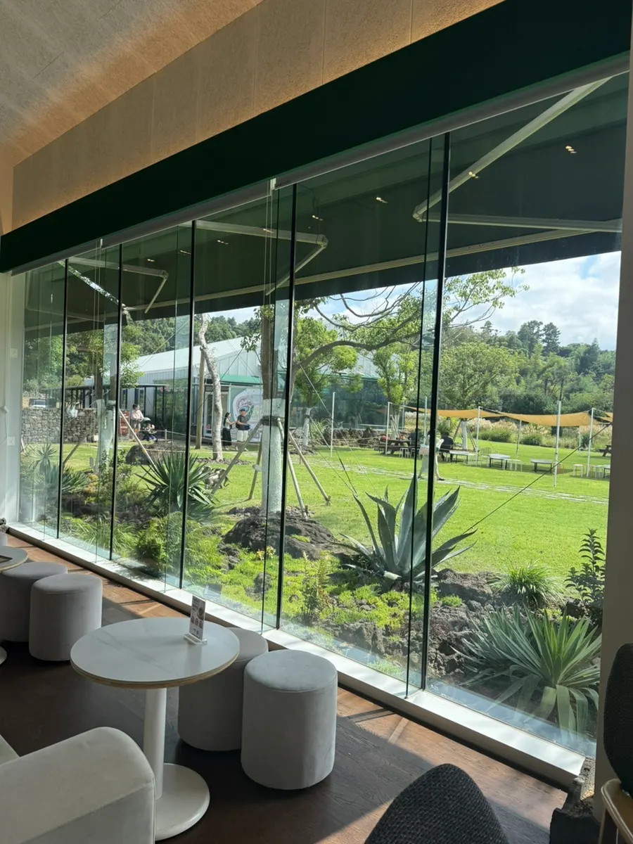 High-ceilinged café interior with garden views through the windows