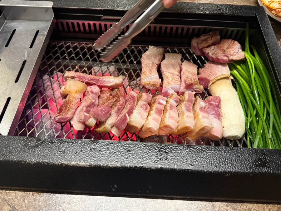 Staff member grilling black pork on the grill plate