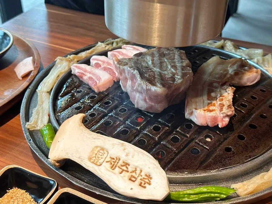 Staff member grilling black pork on charcoal