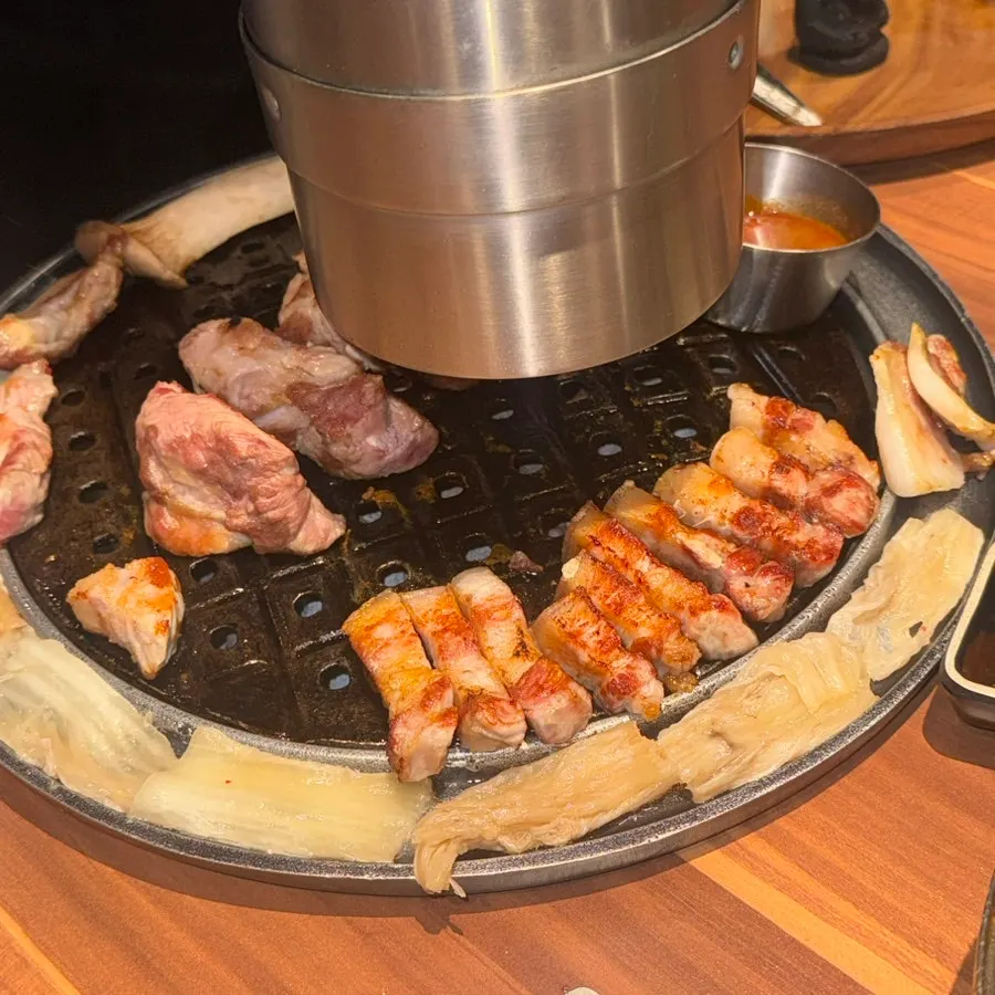 Kimchi grilling alongside black pork on the grill plate