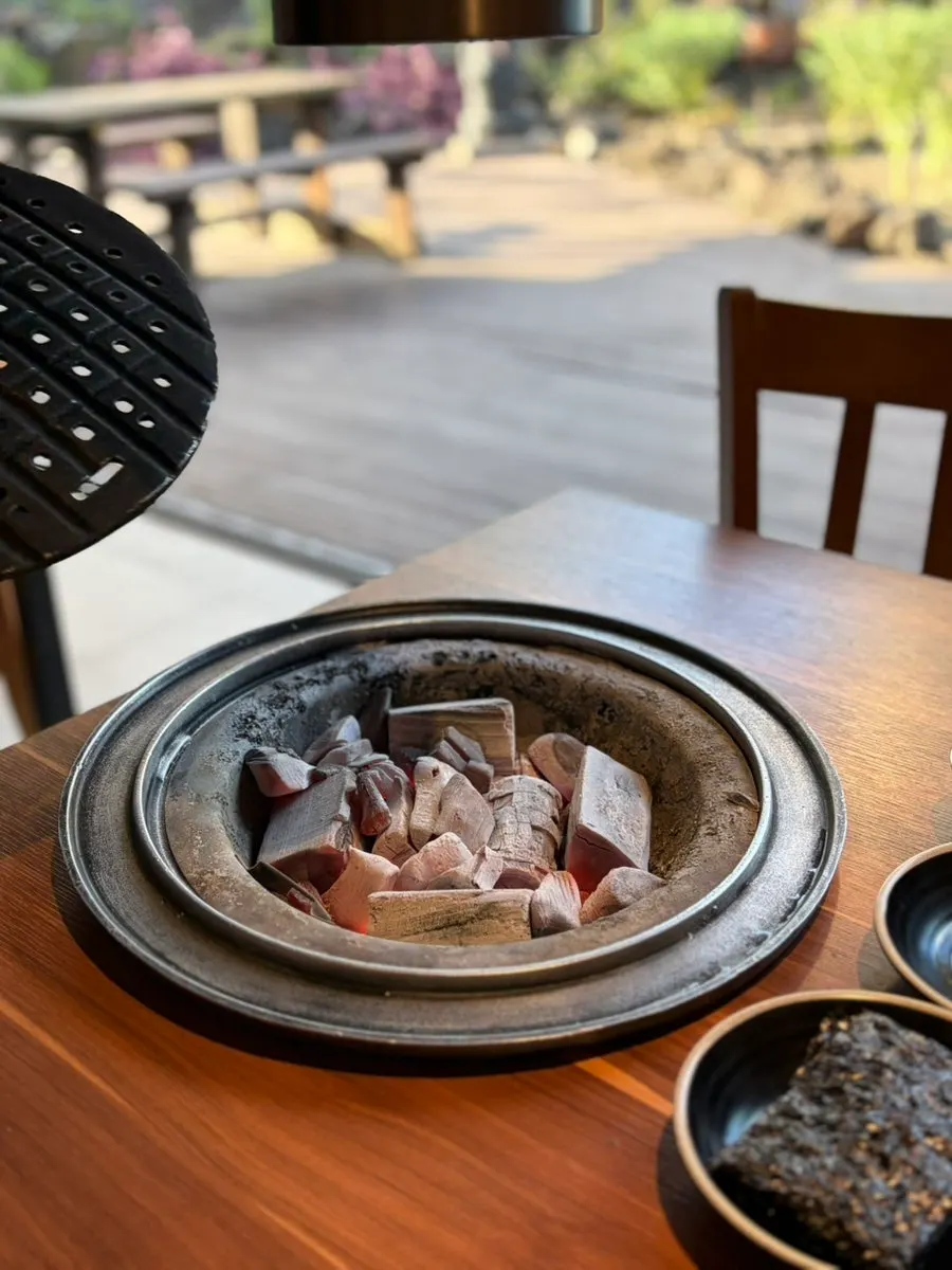 Staff member grilling black pork on the tabletop grill