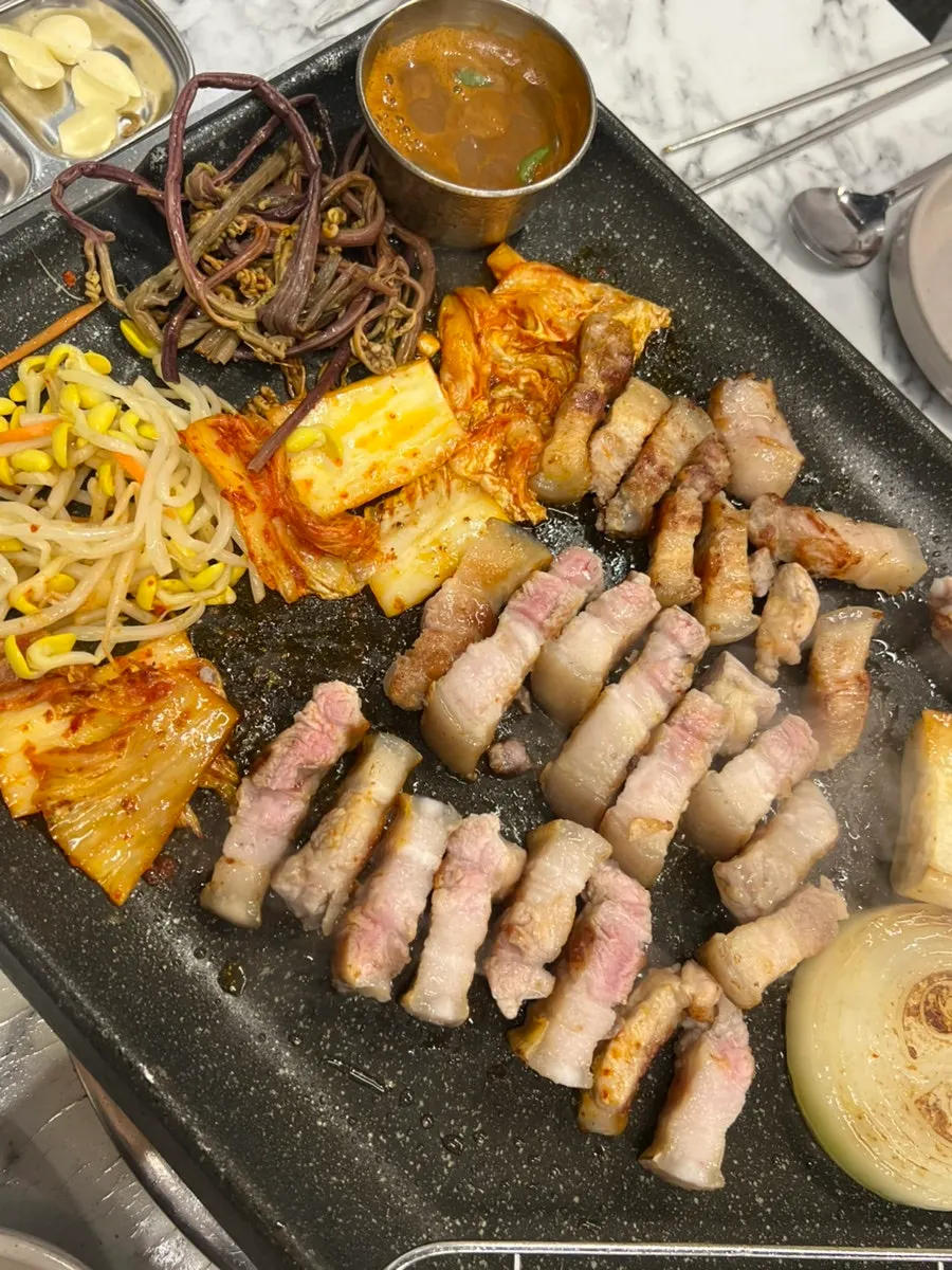 Black pork belly grilling with mushrooms and onions on the stone plate