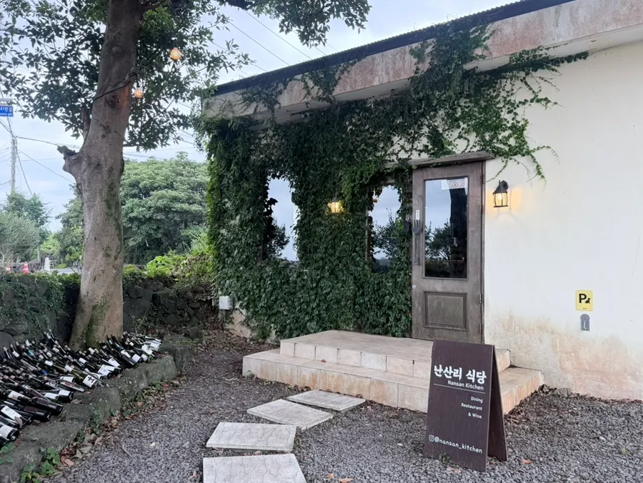 돌담과 나무에 둘러싸인 난산리식당 단층 건물 외관