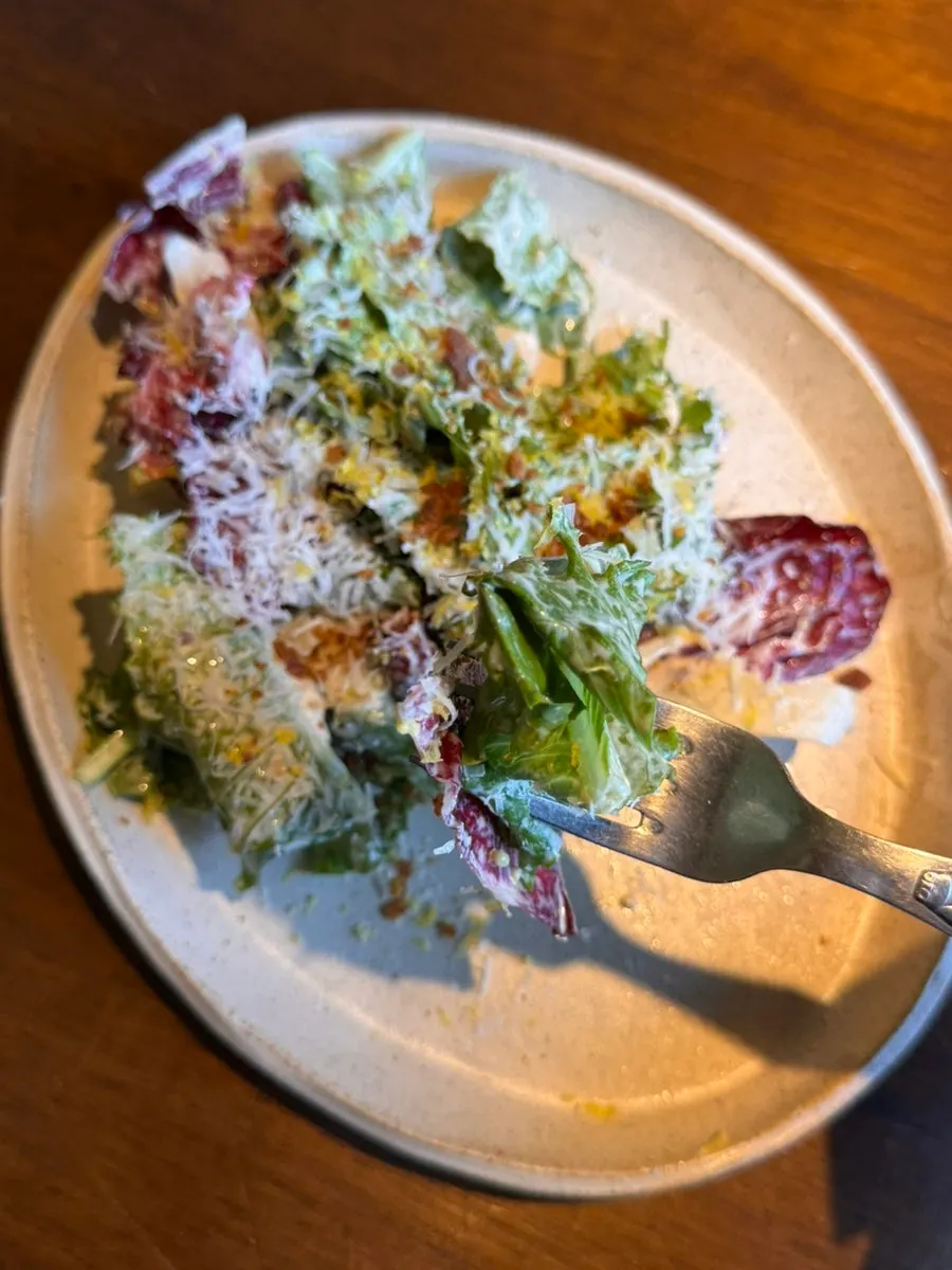 Romaine salad topped with caesar dressing, bacon, and parmesan