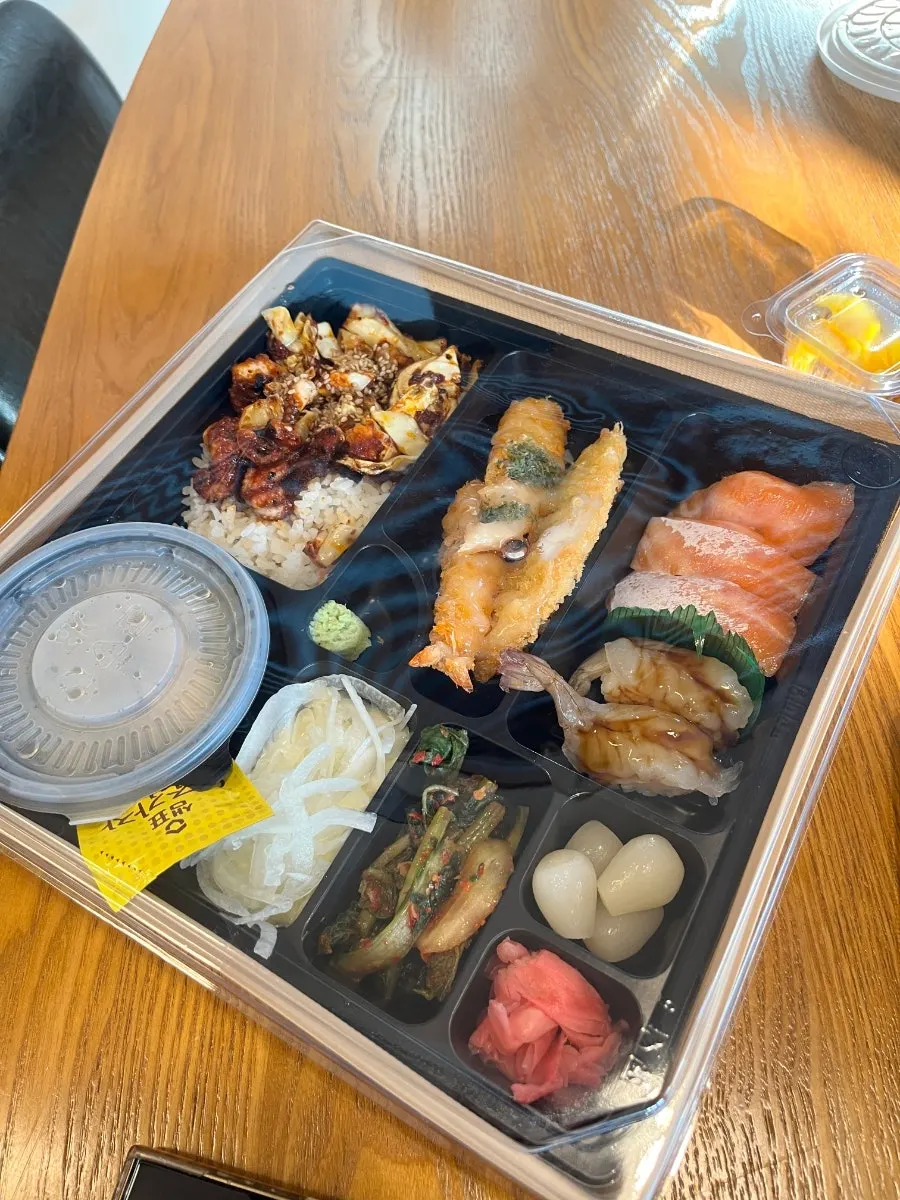 Jejju Lunchbox with raw salmon sushi, shrimp sushi, tempura, and stir-fried baby octopus