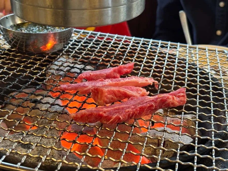 숯불 불판 가장자리에서 구워지는 갈비살