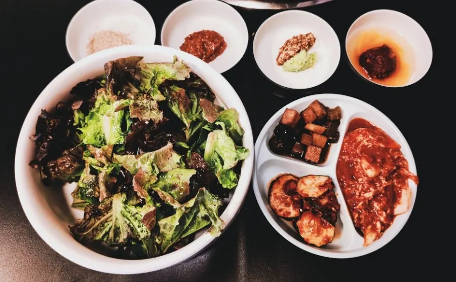 Basic table setting with dressed lettuce, pickles, and assorted sauces