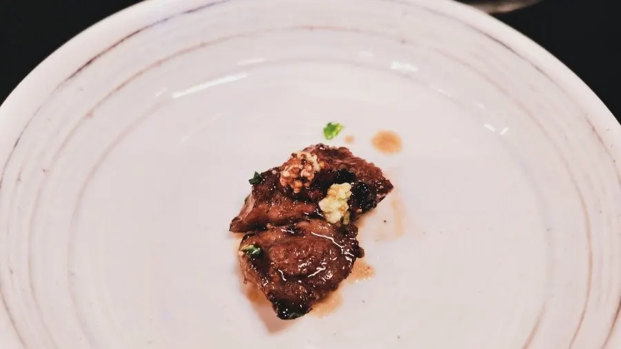 A piece of galbisal topped with wasabi, wholegrain mustard, and Dolgyeok sashimi sauce