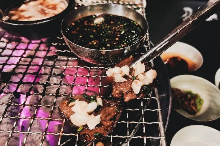 Galbisal dipped in garlic-chili soy sauce and topped with manong sauce
