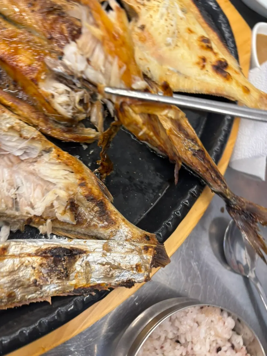 Picking apart the flesh of grilled mackerel
