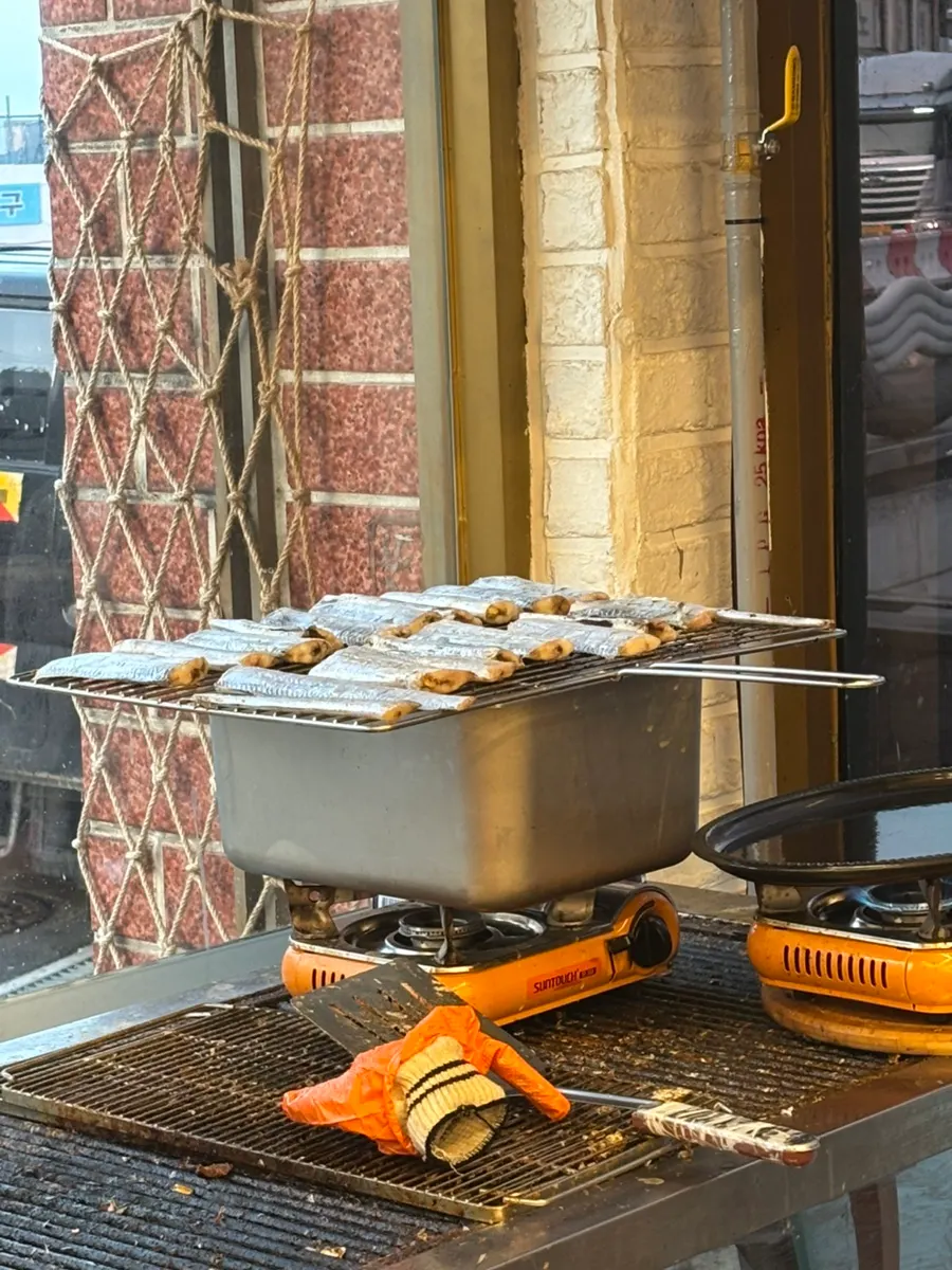 Owner grilling fish over charcoal