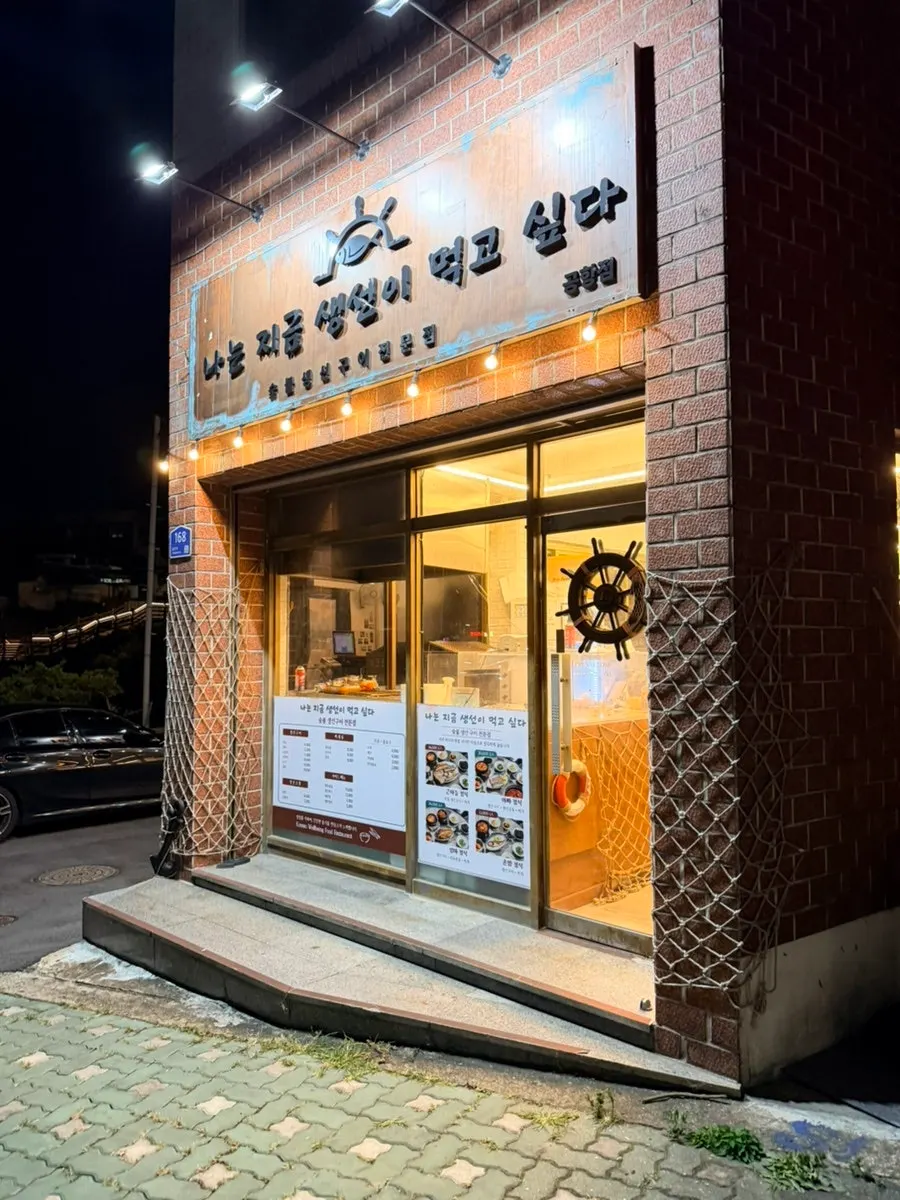 밤에 밝게 켜진 나는지금생선이먹고싶다 용담공항점 간판