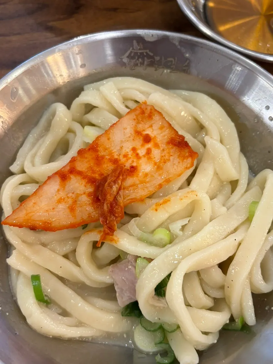 Mandu dipped in broth alongside emptied side dish plates