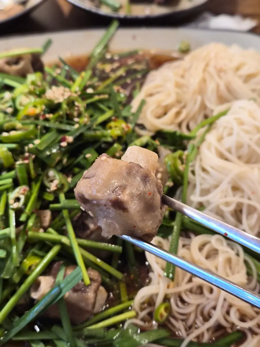 素麺をニラと一緒に包んで食べる様子