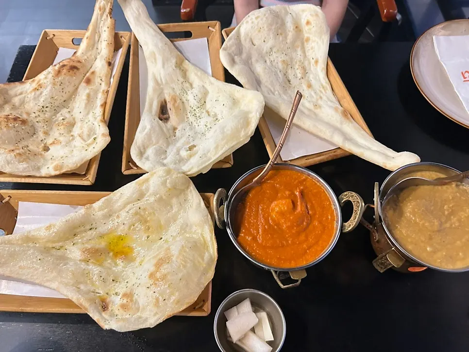 Table set with chicken korma, shrimp makhani, and naan