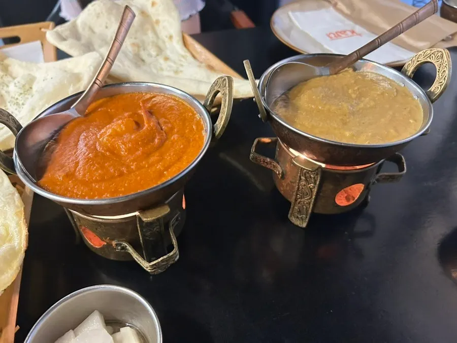 Two curry bowls kept warm over a flame