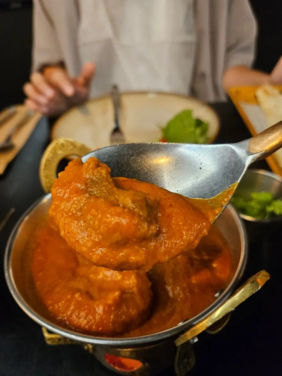 A side plate of cilantro requested separately, next to curry
