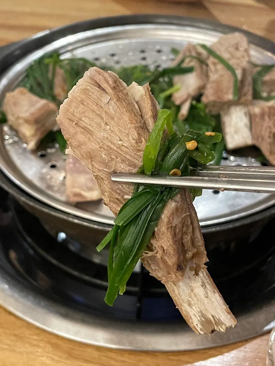 A piece of boiled lamb rib picked up with chives