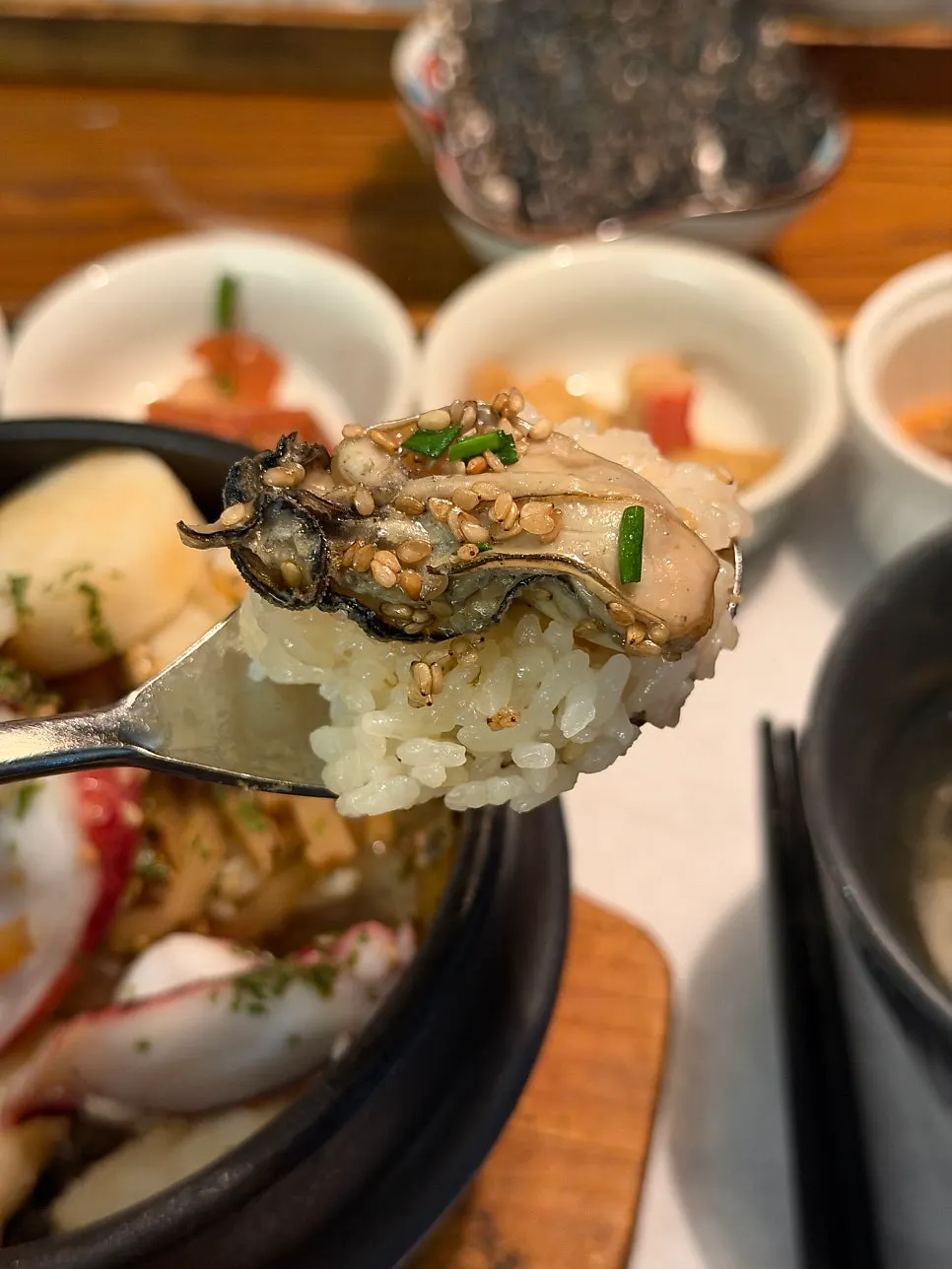 A spoonful of seafood sotbap topped with oyster