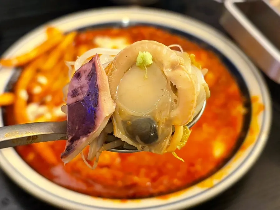 Scooping out broth and seafood to eat