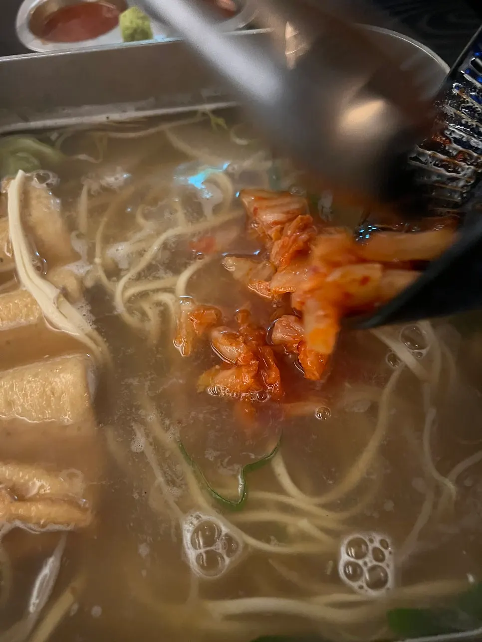 Kimchi kalguksu topped with well-fermented sour kimchi