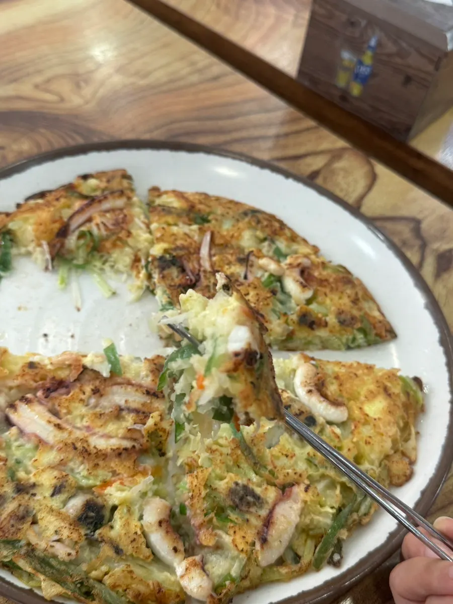 A piece of seafood pancake picked up with chopsticks