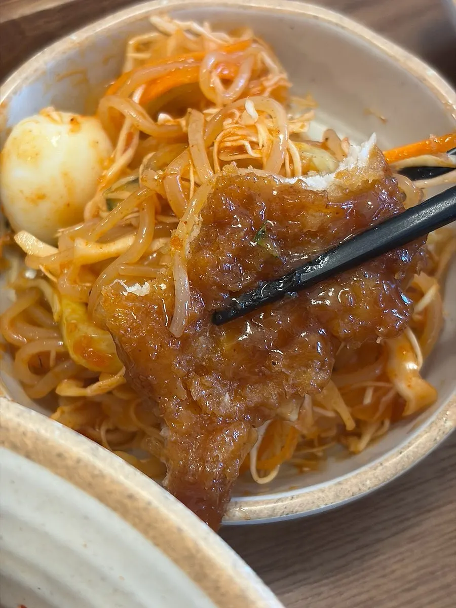 Chopsticks lifting a strand of jjolmyeon noodles