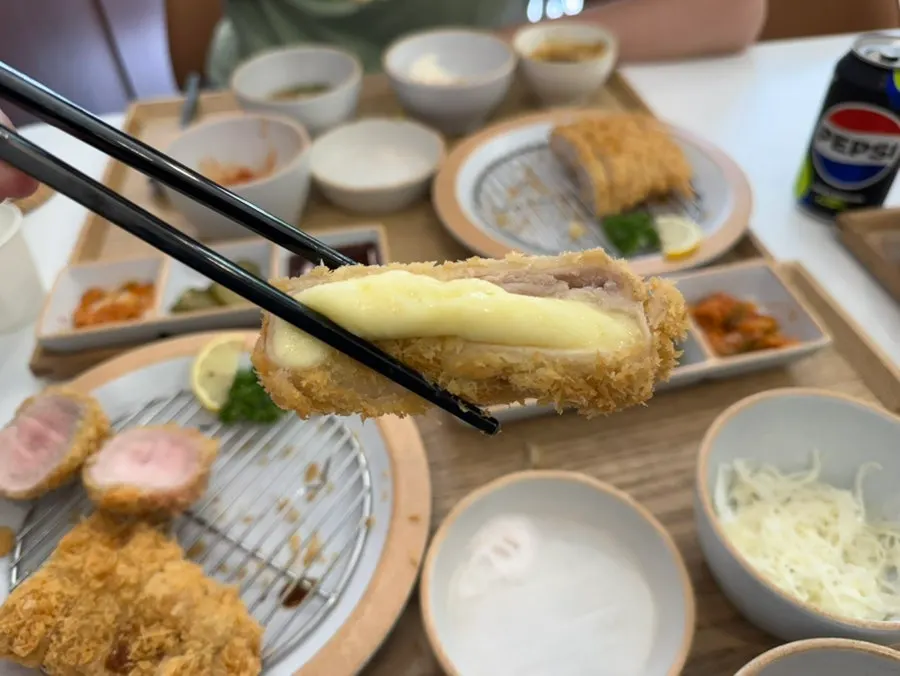 Cross-section of cheese katsu dipped in katsu sauce