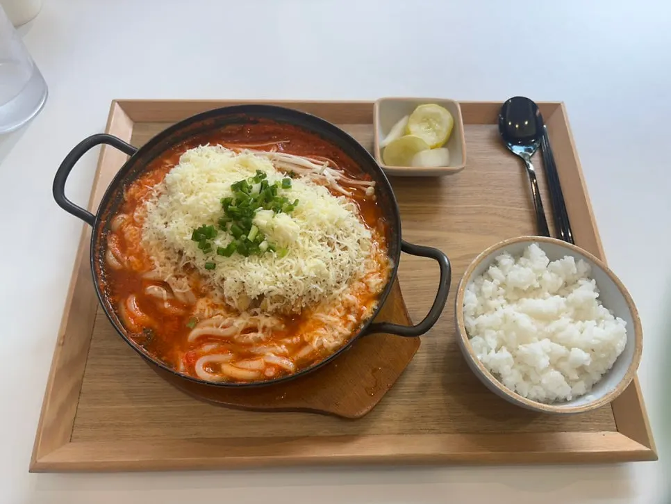 Kimchi cheese nabe topped with cheese, served with a bowl of rice