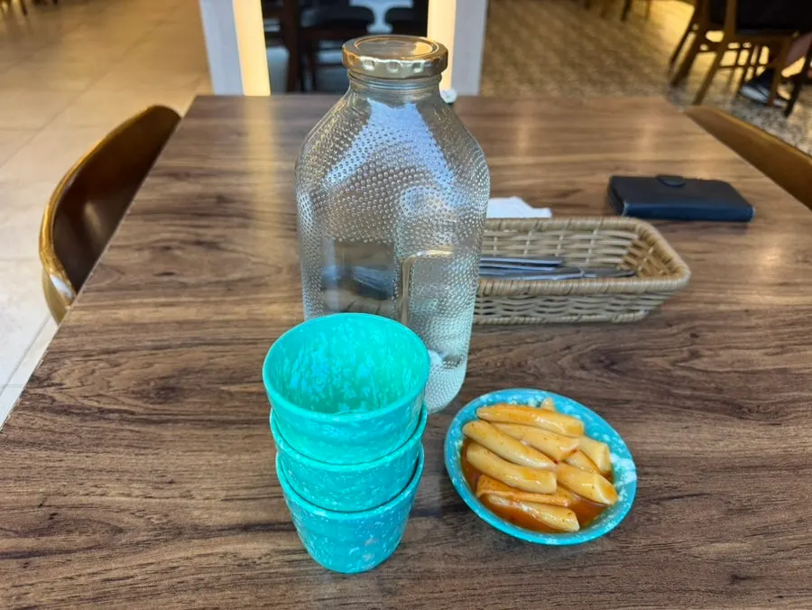 Water in a glass Del Monte bottle with a retro green cup setting