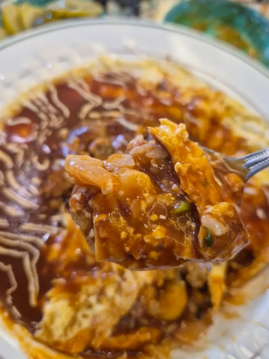 Scooping a bite of hamburg steak omurice with cut steak