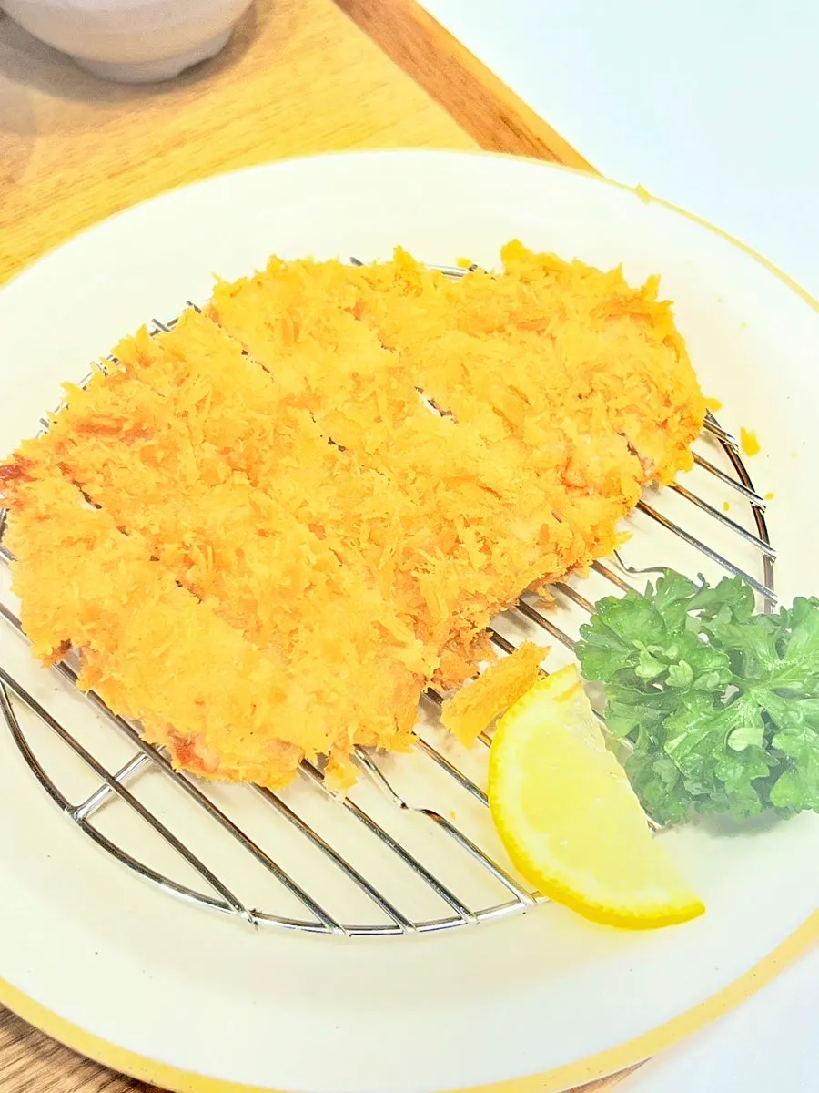 A piece of pork loin katsu picked up with chopsticks