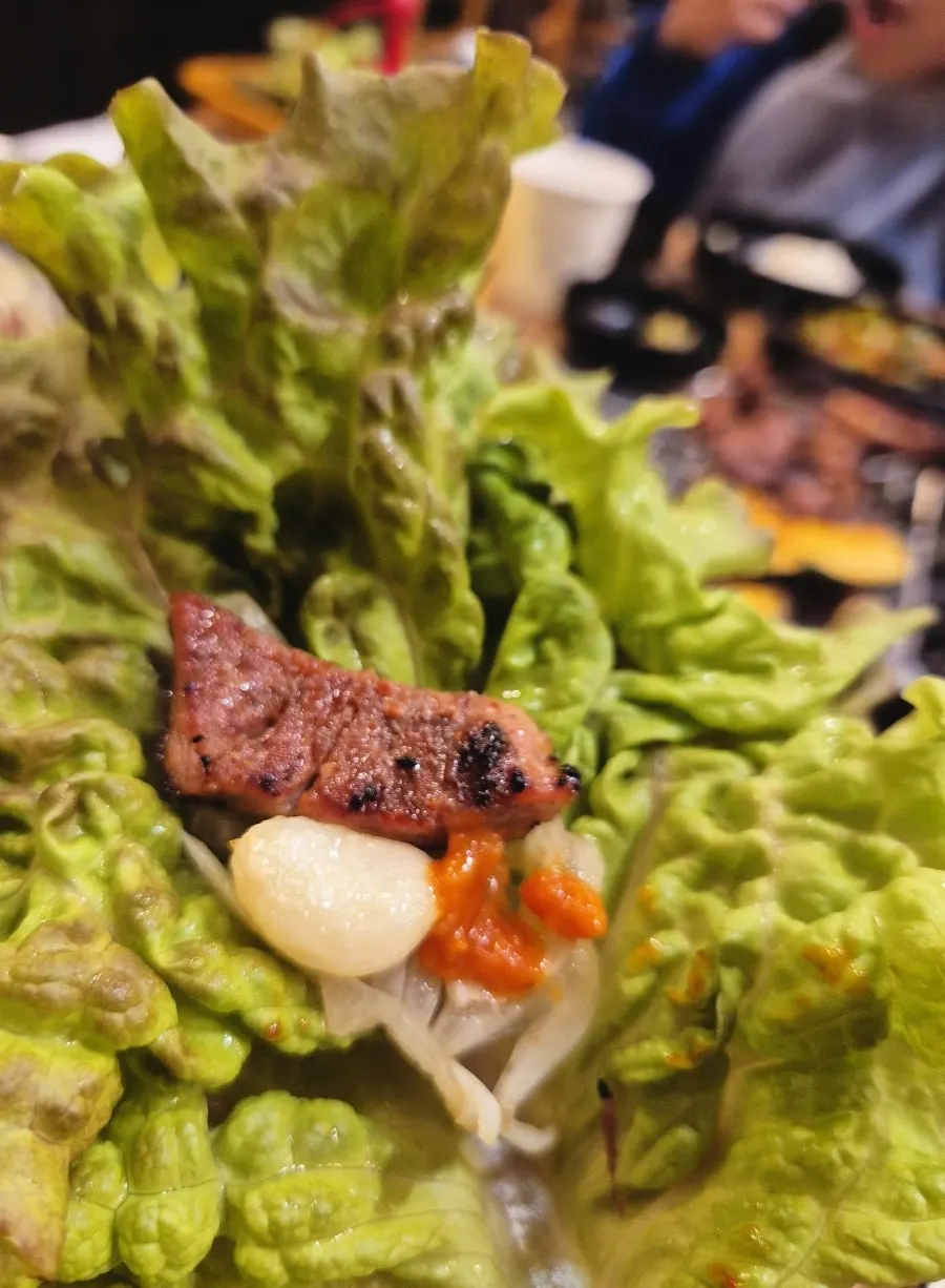쌈 채소에 올린 숯불 갈비 한 점