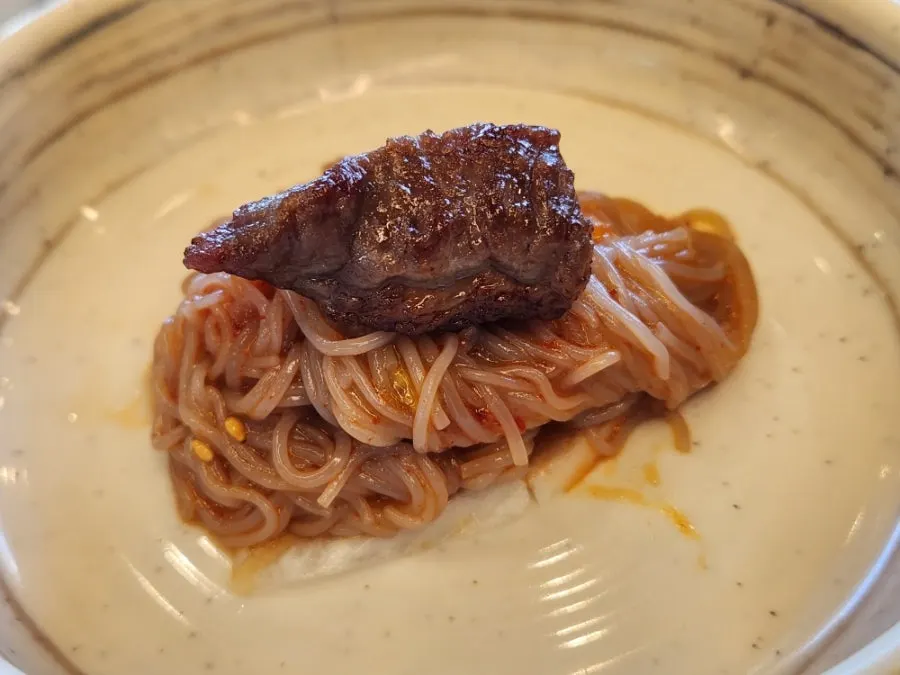 Wrapping sogalbisal in bibim-naengmyeon to eat