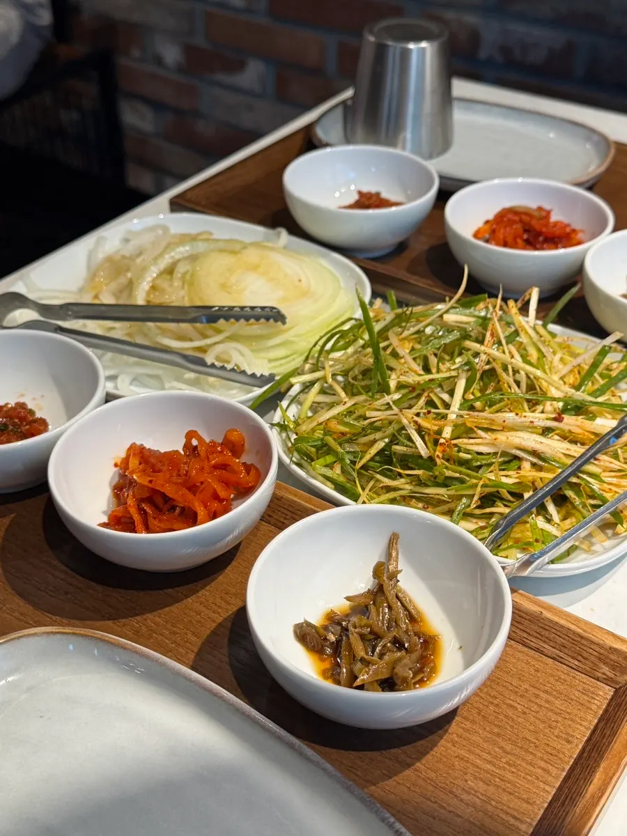 Basic side dishes at Jeongyukdo including pickled onions and shredded scallion salad