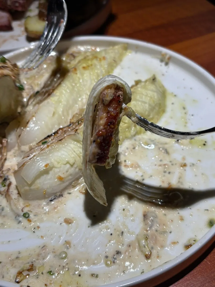 A bite of pork belly steak wrapped in grilled cabbage