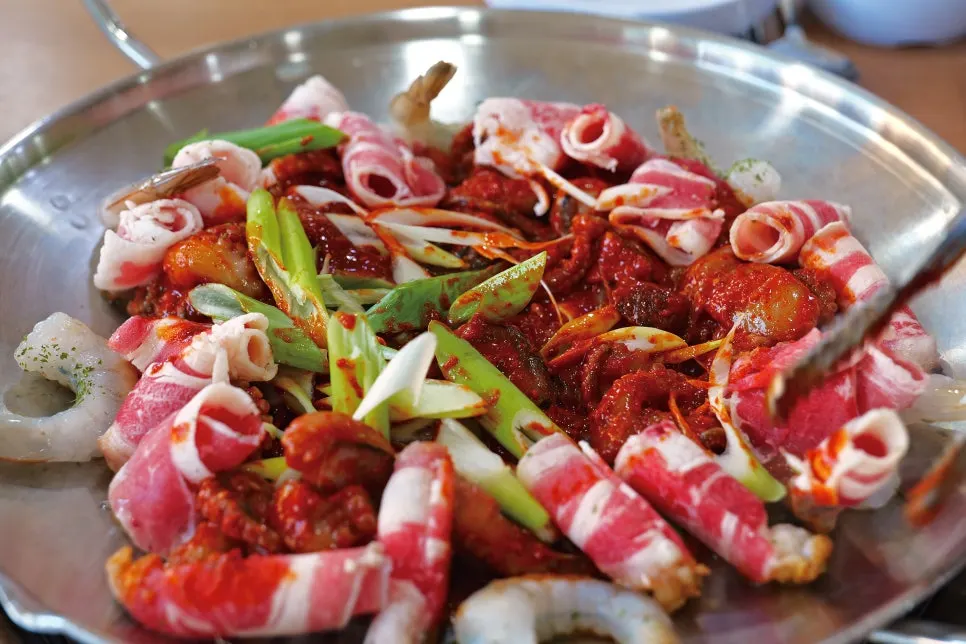 A staff member stir-frying the Hwasae on the griddle