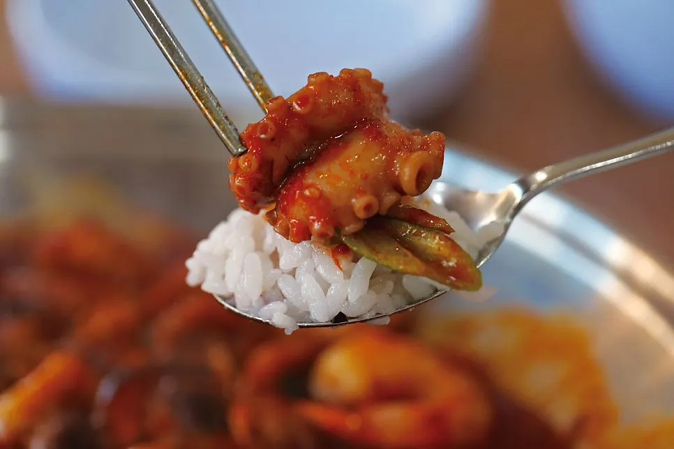 Chopsticks lifting a piece of spicy octopus