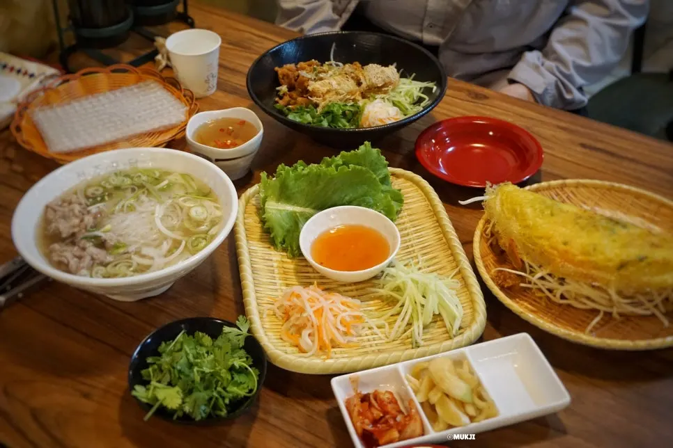 Full table with pho, banh xeo, and bun cha at Phodam